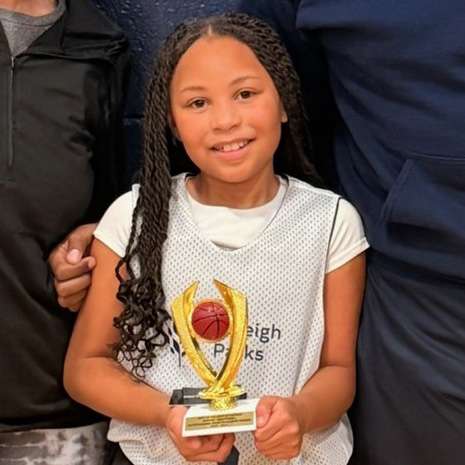 a child smiling with a trophy for winning the sportsmanship award