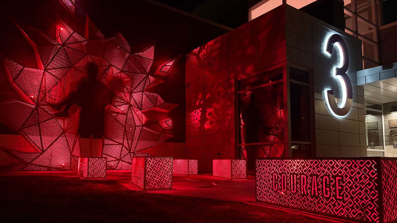 An image of the artwork lit at night glowing red.