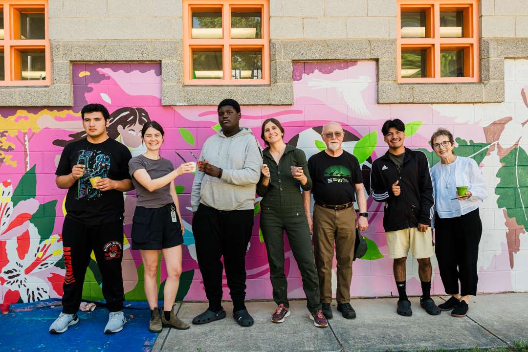 Artist Eli Arguello with teen students painting