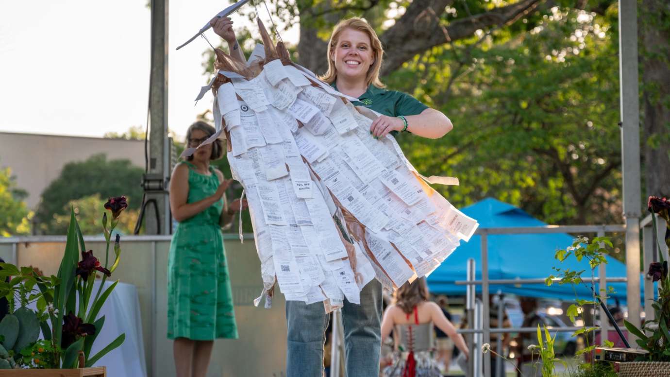 Girl holding dress made of paper receipts