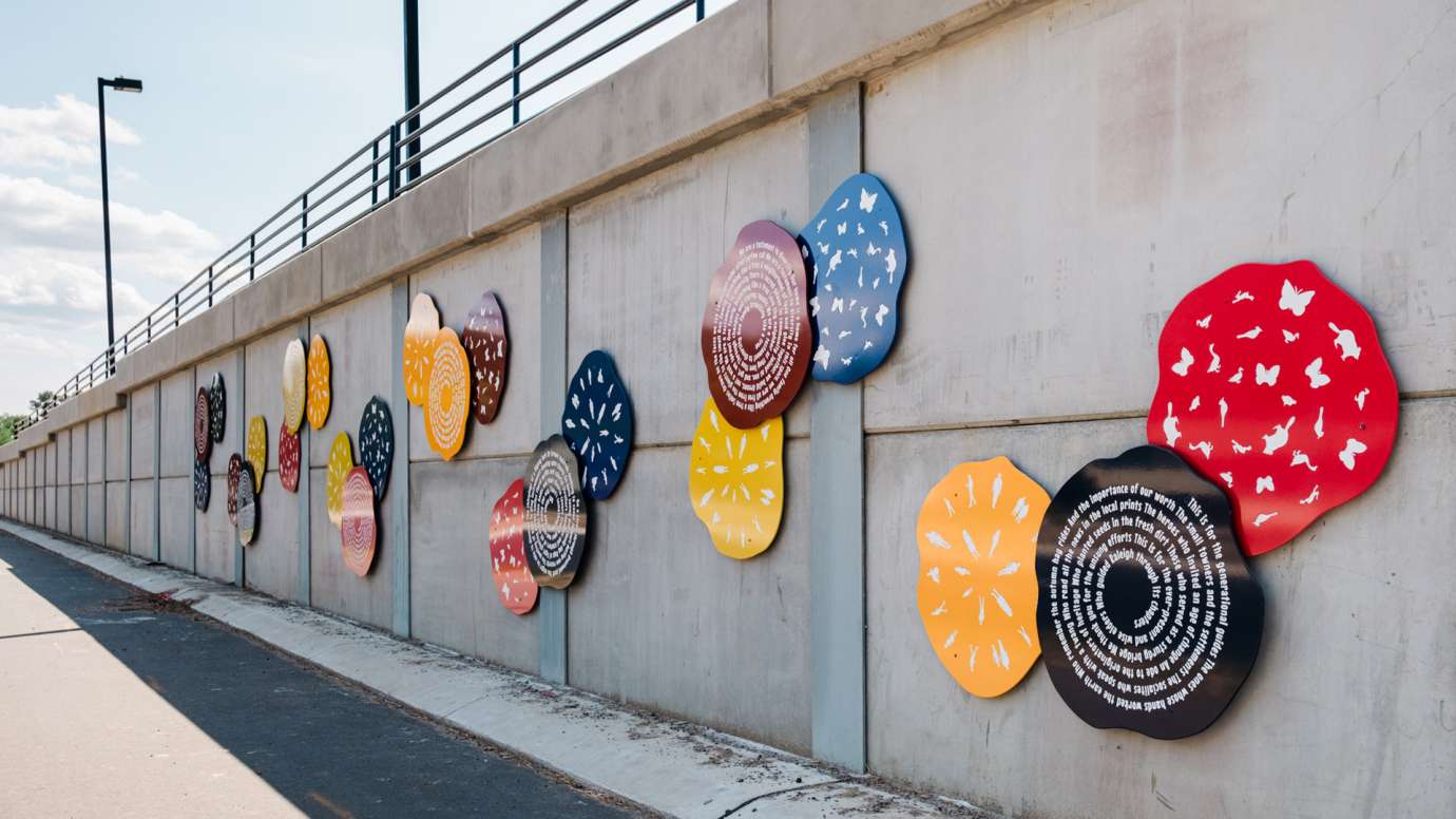 Colorful discs line a wall along a roadway