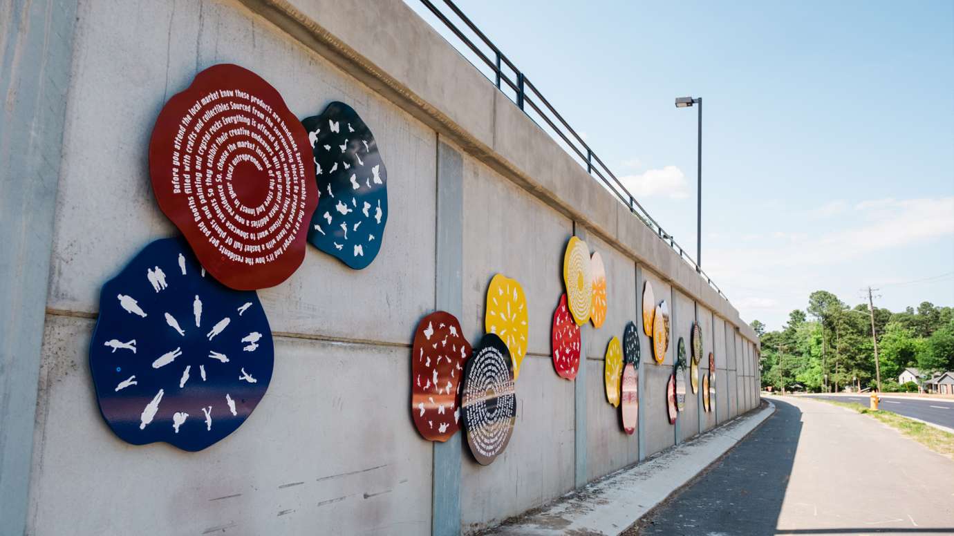 Colorful discs line a wall along a roadway