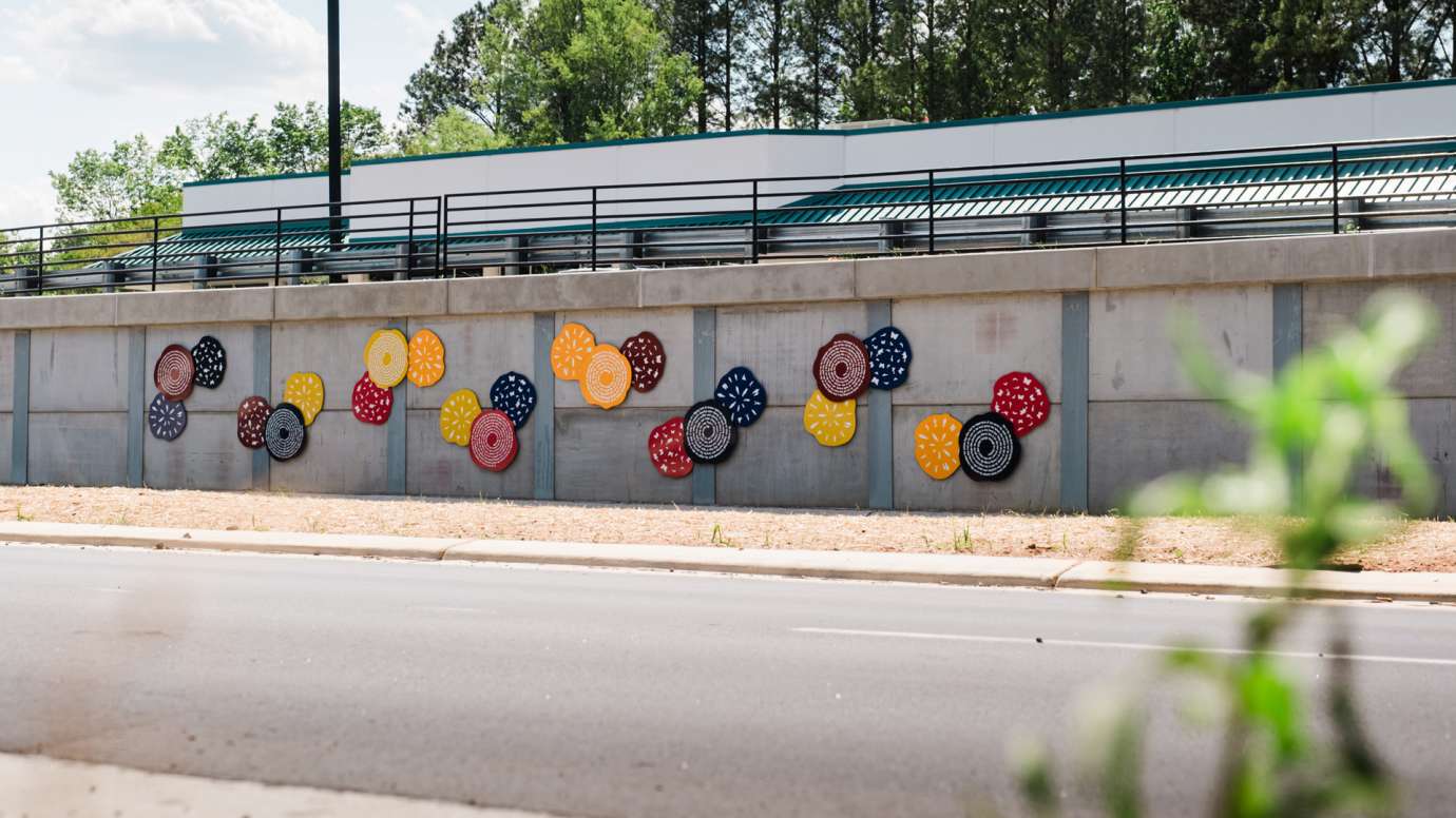 Colorful discs line a wall along a roadway