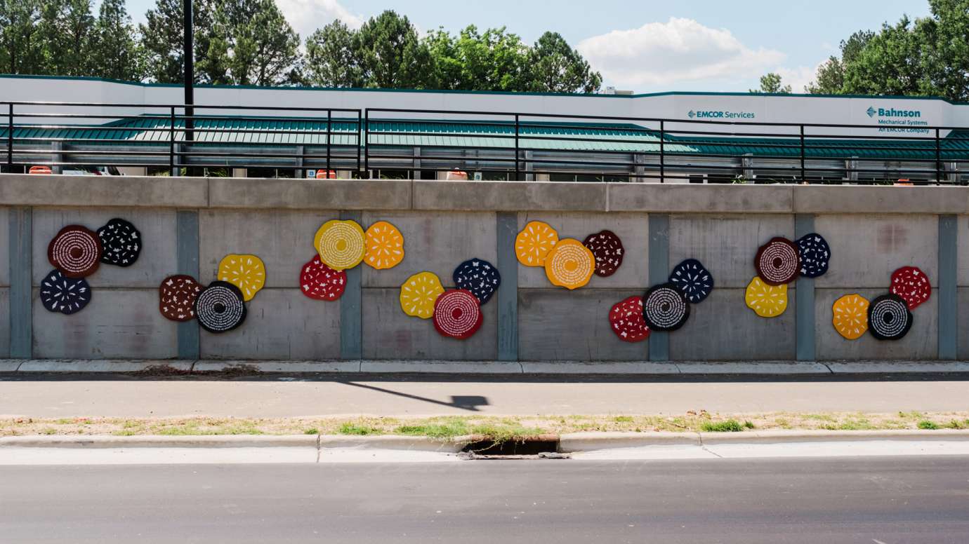 Colorful discs line a wall along a roadway