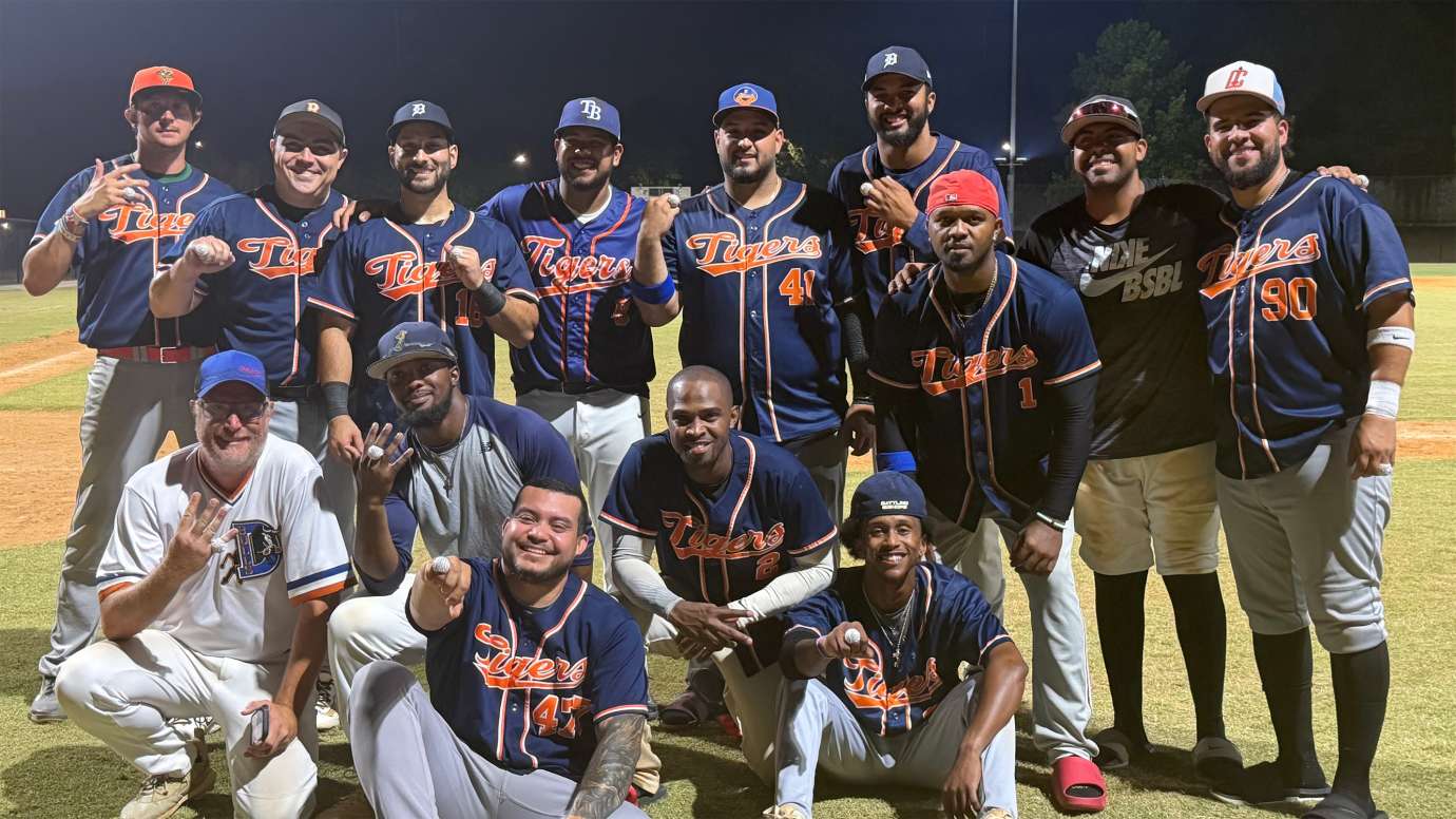 an adult baseball team wearing blue Tigers jerseys and smiling