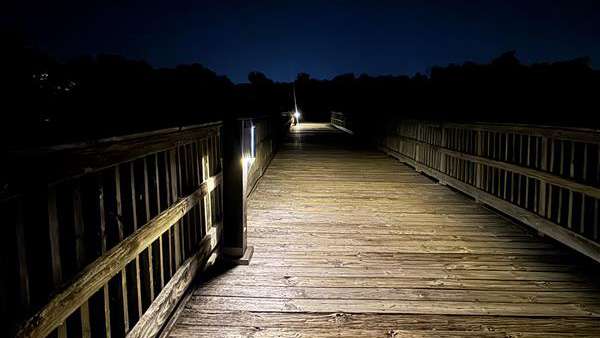 a greenway trial bridge at night with solar lights