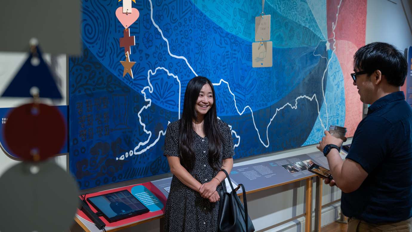 a person standing in front of art while talking to a friend