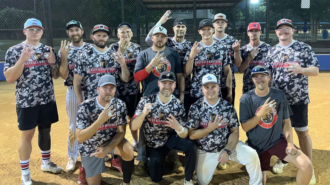 a group of adults smiling after winning a softball championship
