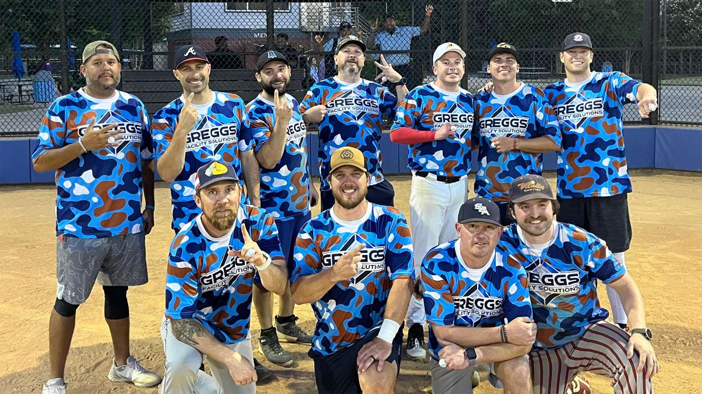 a group of adults smiling after winning a softball championship