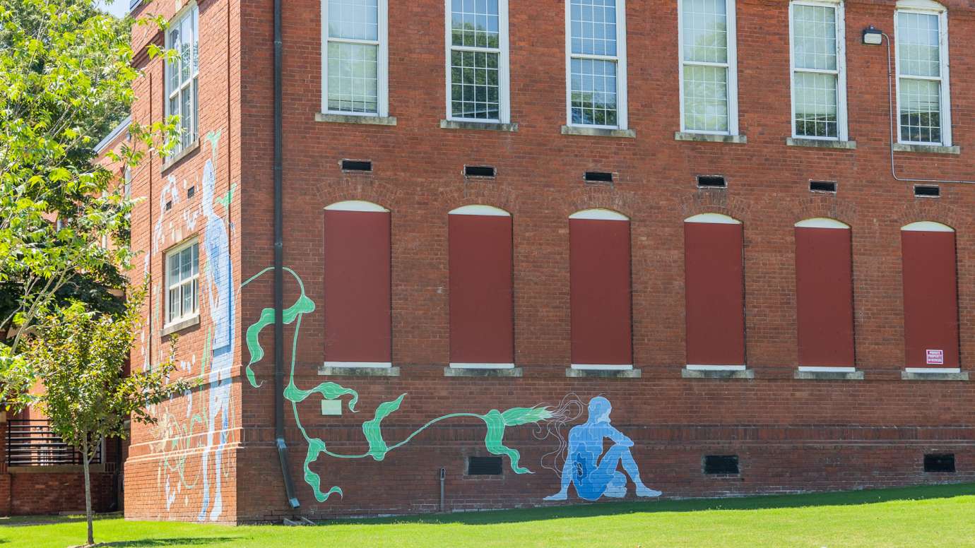 A watery blue figure is painted on a brick wall. 