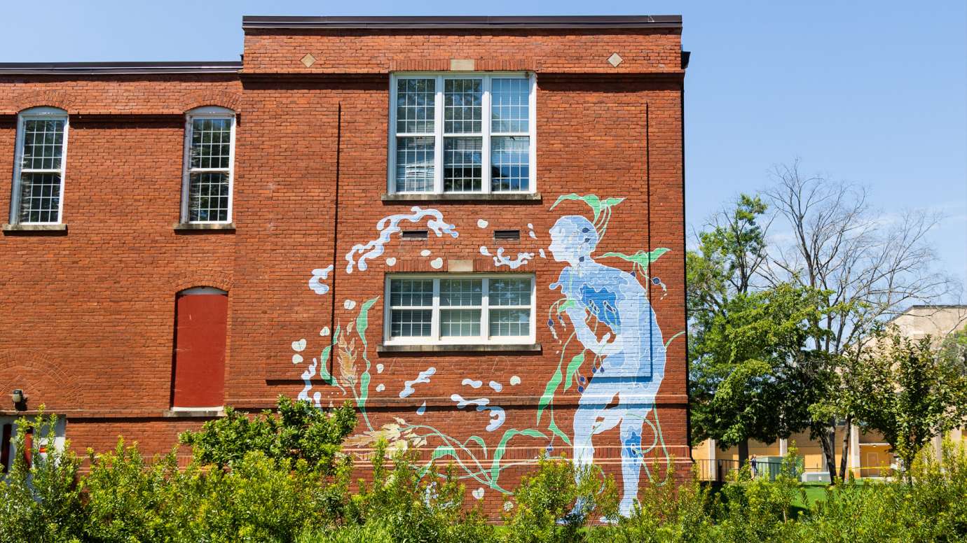 A watery blue figure is painted on a brick wall. 