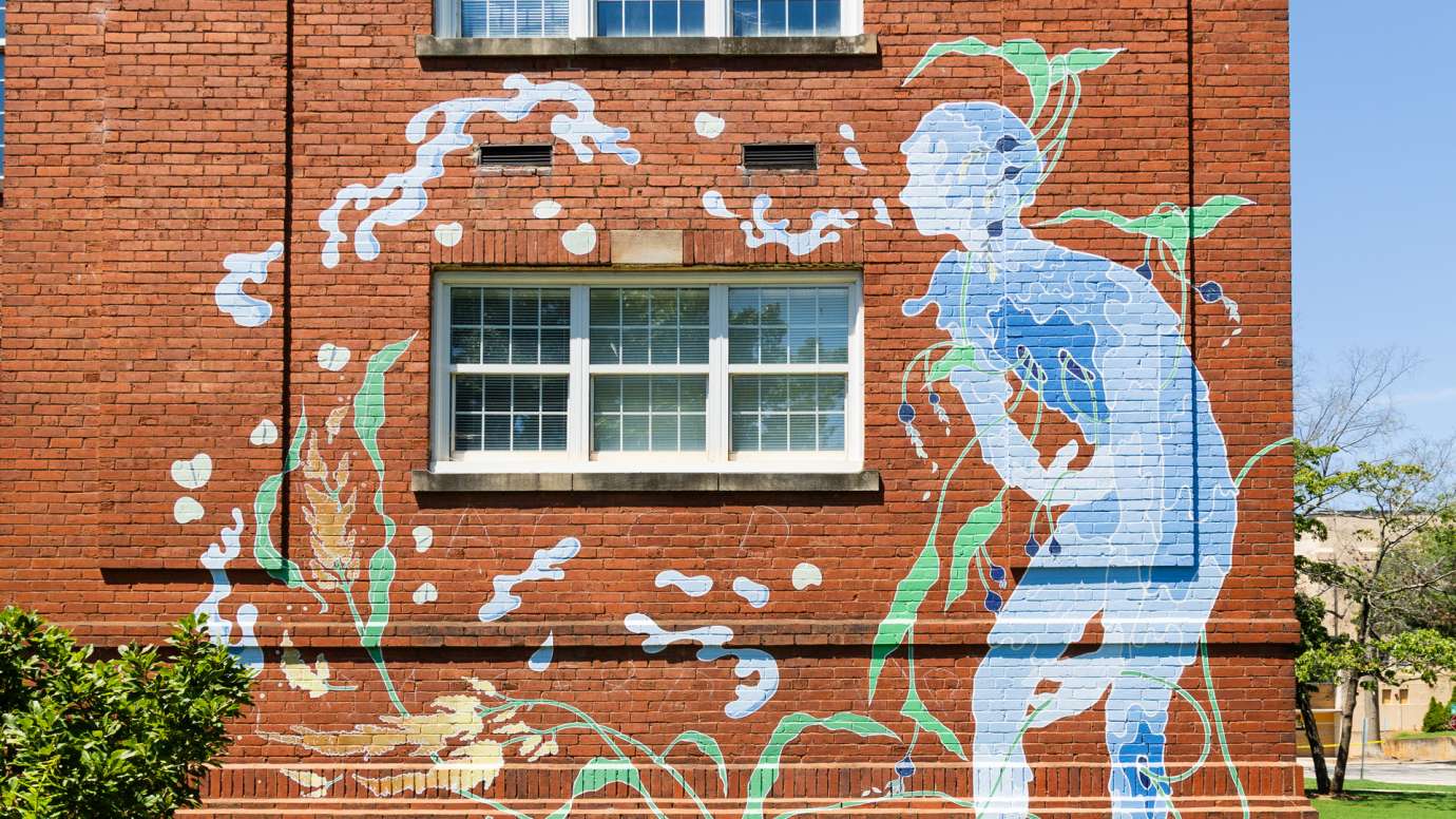 A watery blue figure is painted on a brick wall. 