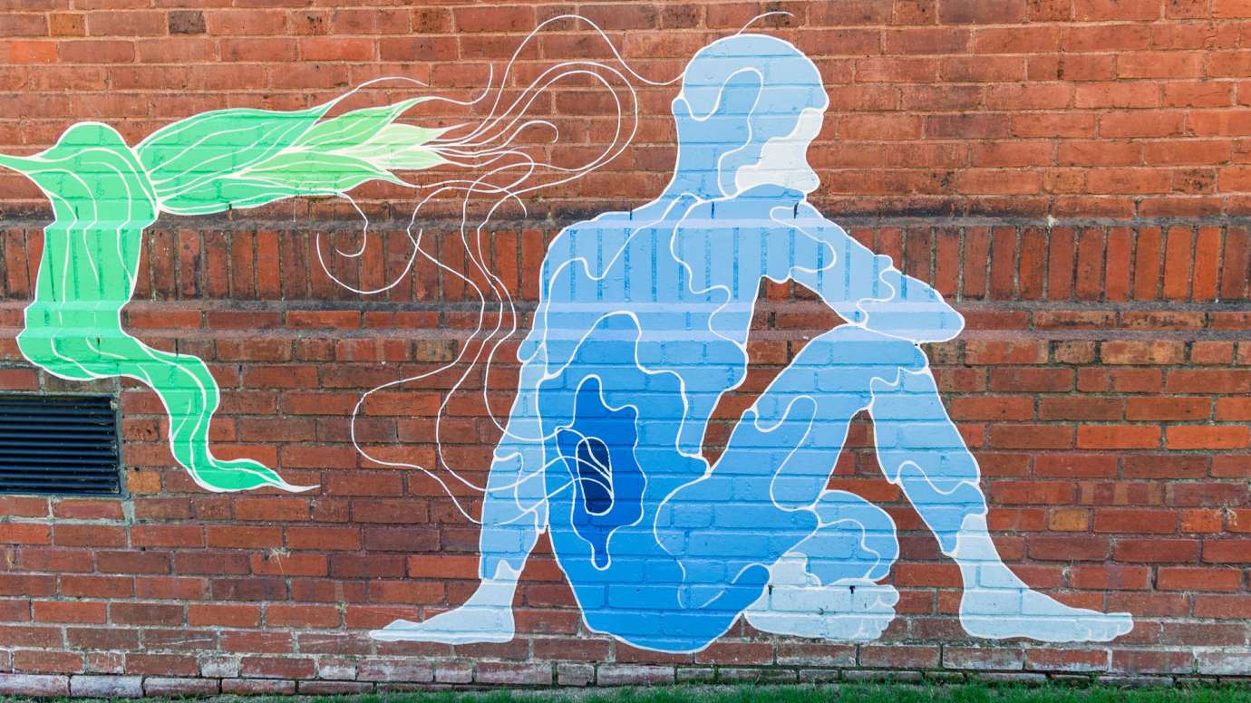 A watery blue figure is painted on a brick wall. 