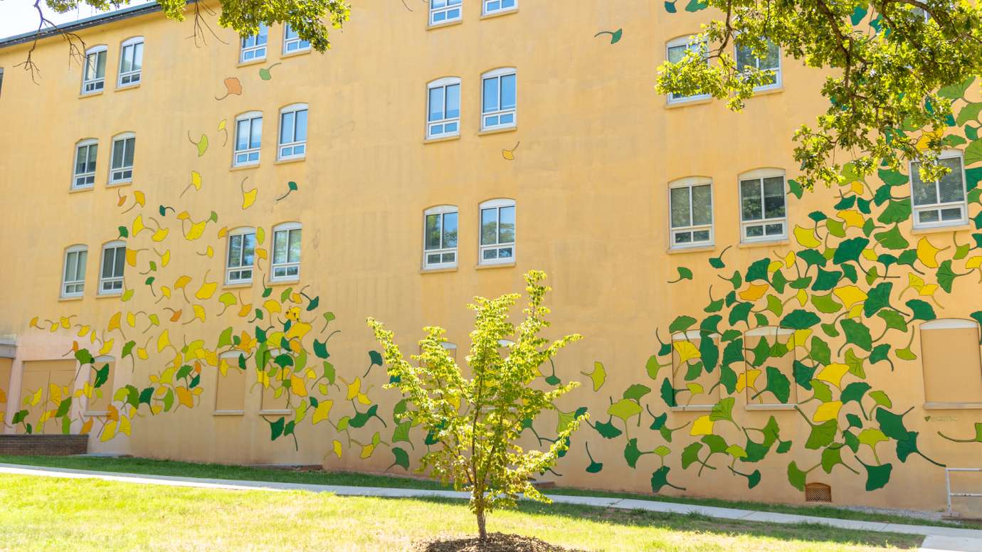 A yellow building is painted with ginkgo leaf shapes in yellow, green, and orange.