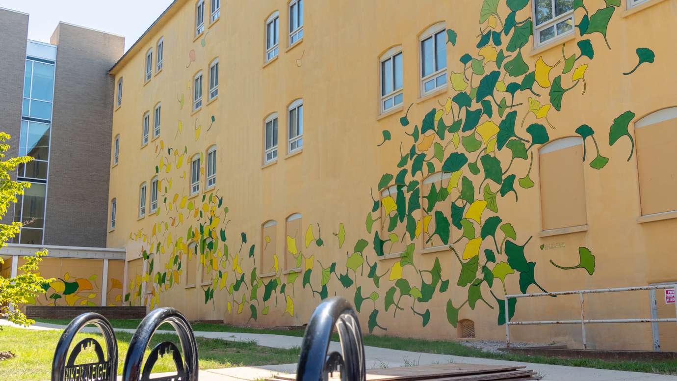 A yellow building is painted with ginkgo leaf shapes in yellow, green, and orange.