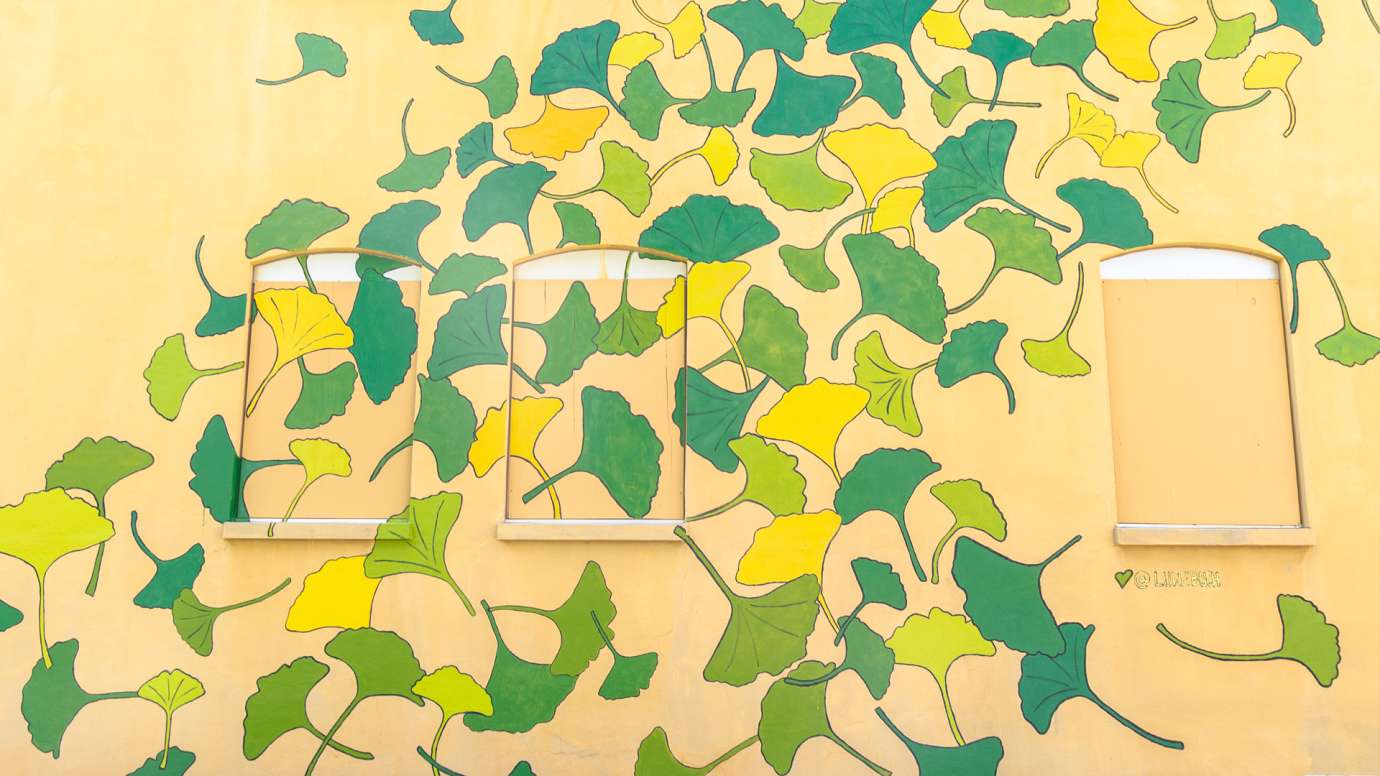 A yellow building is painted with ginkgo leaf shapes in yellow, green, and orange.