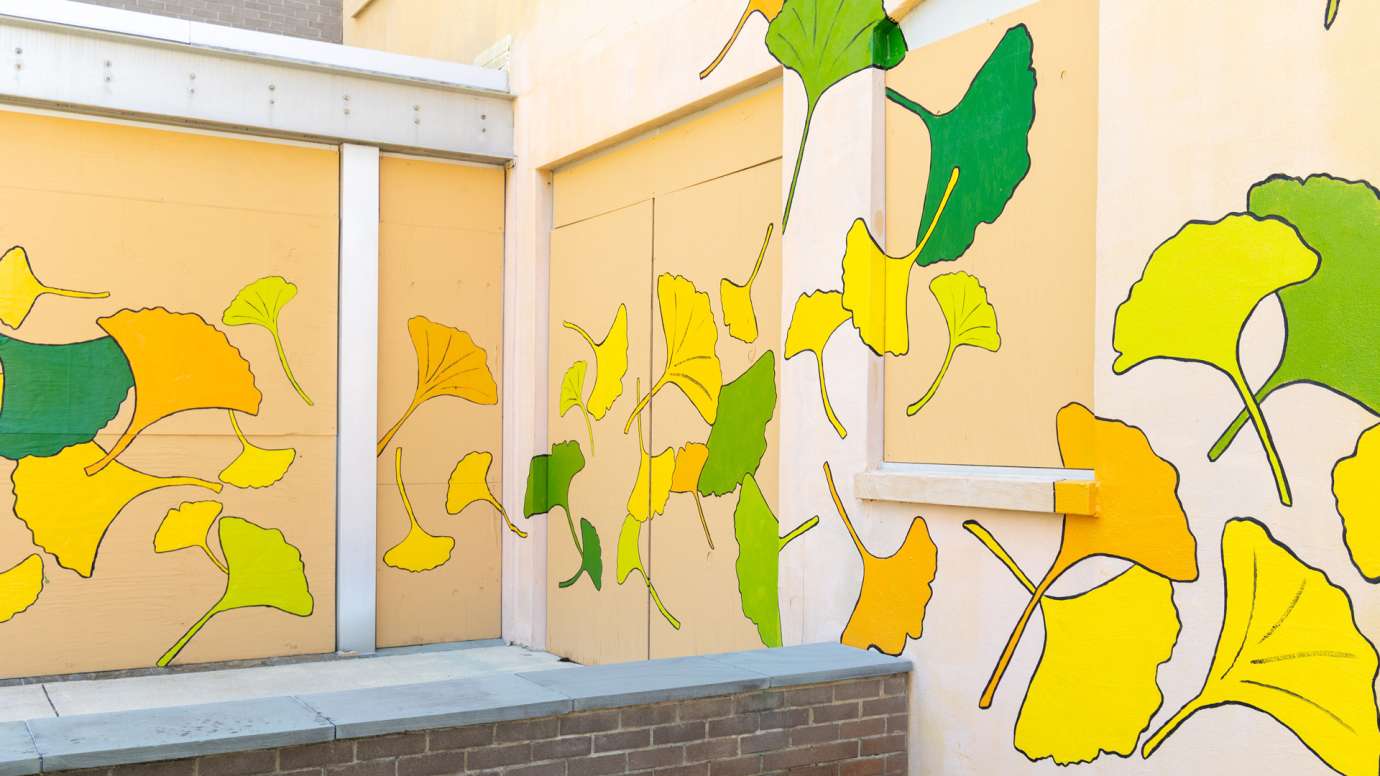 A yellow building is painted with ginkgo leaf shapes in yellow, green, and orange.