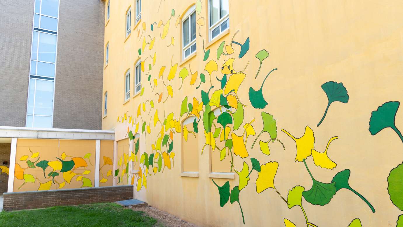 A yellow building is painted with ginkgo leaf shapes in yellow, green, and orange.