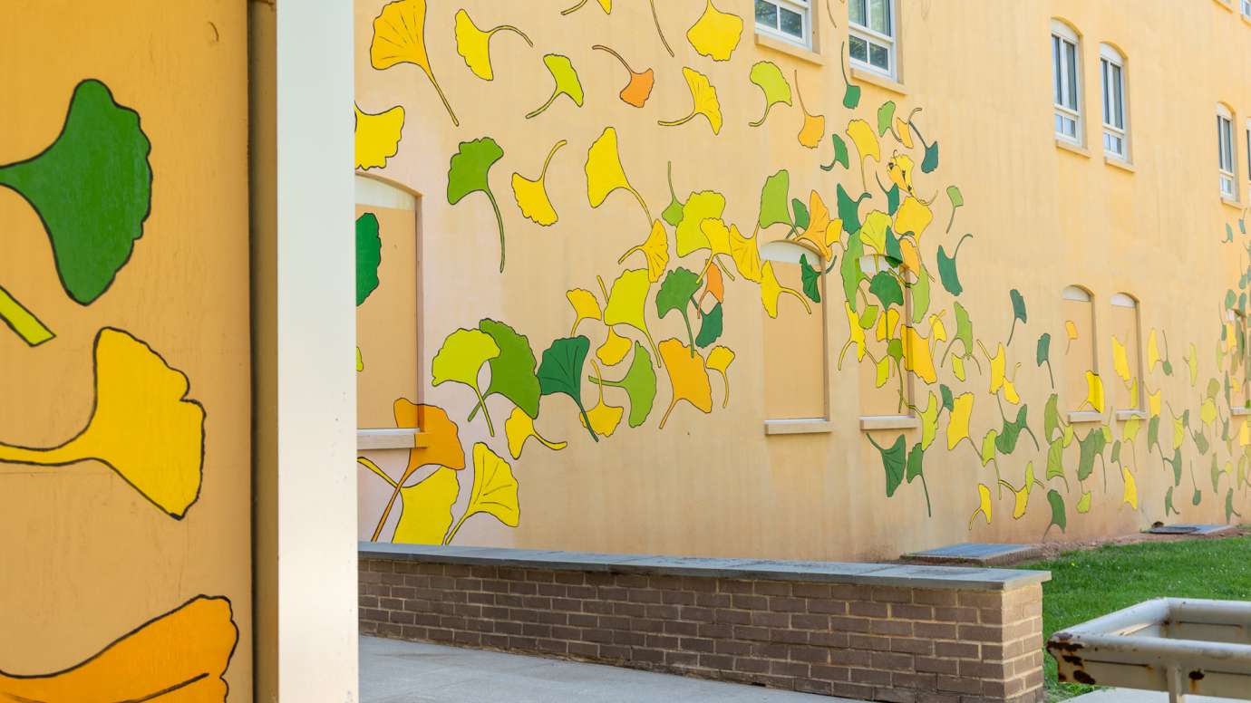 A yellow building is painted with ginkgo leaf shapes in yellow, green, and orange.