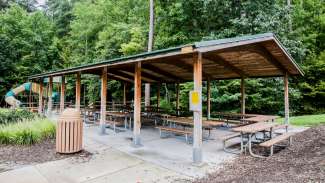 A large outdoor picnic shelter with multiple tables 