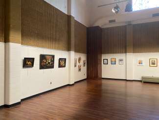 paintings hanging in a large room with white walls and a wooden floor