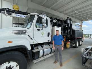 A photo of Jason Holmes standing in front of a large City of Raleigh truck