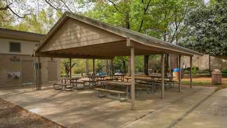 A large outdoor picnic shelter with six tables 