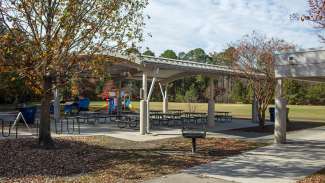 A large outdoor picnic shelter with multiple tables 