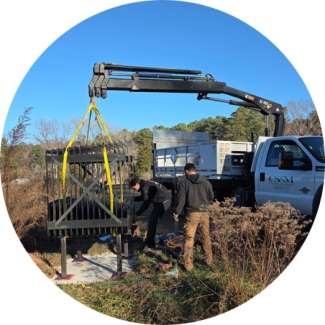 A large, scope-like structure being installed by a crane on a prairie.