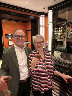 Couple smiling at the camera raising wine glasses in celebration of an art event