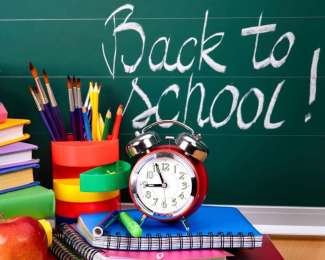 School supplies in front of a chalkboard with back to school written on it