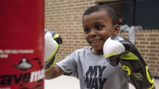 a child wearing boxing gloves practicing punching